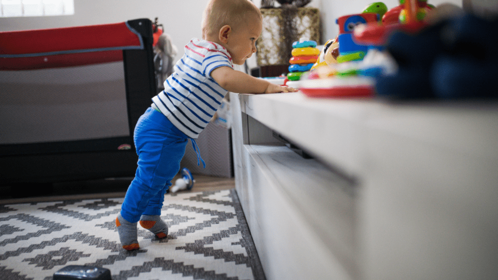 baby standing on toes while leaning on shelf